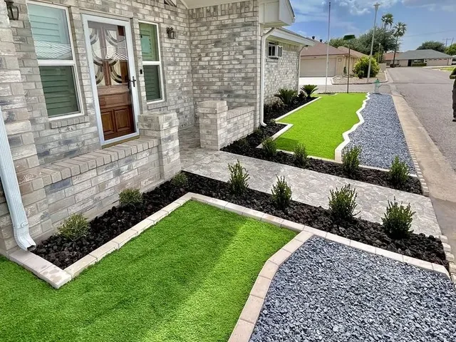 A stone-fronted house with a strip of lawn, a gray gravel path curving past it and black-edged beds of low shrubs